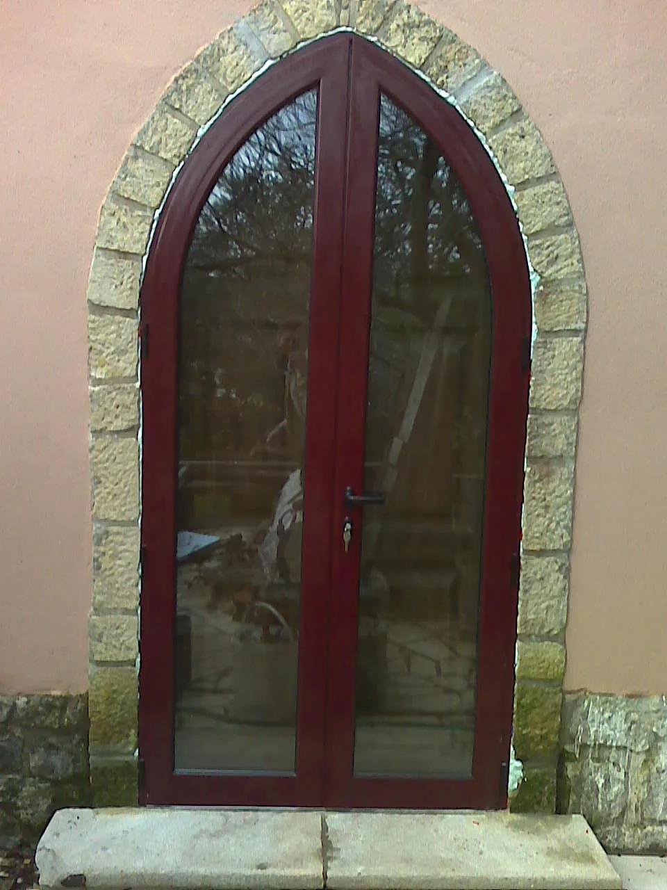 Porta envidraçada em PVC com duas folhas e remate superior em arco
