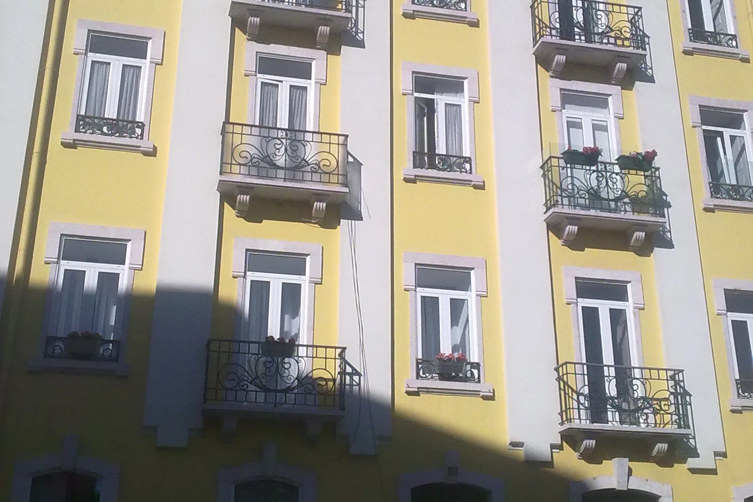 Fachada urbana tradicional com várias janelas brancas em PVC